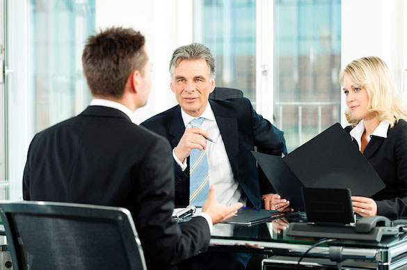 Three people seated during a finance job interview